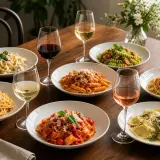 Ein Festmahl mit verschiedenen Pastagerichten und Gläsern mit Rot-, Weiß- und Roséwein. Perfekt für ein Abendessen mit Freunden, wo jeder sein Lieblings-Wein zu Pasta genießen kann.