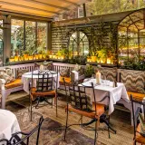 Gemütliche Terrasse mit Tischen, Kerzen und Pflanzen. Einladendes Ambiente für ein schönes Essen. Design und Genuss vereint.