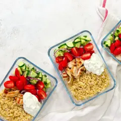Drei Glasbehälter mit Reis, gegrilltem Hähnchen, Tomaten, Gurken und Zwiebeln – perfekte gerichte zum vorkochen für die Woche.