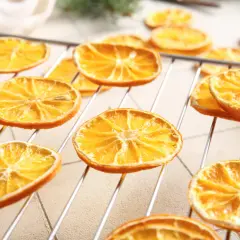 Getrocknete Orangenscheiben auf einem Rost, bereit zum Trocknen. So trocknet man Orangenscheiben für Dekorationen oder zum Verzehr.