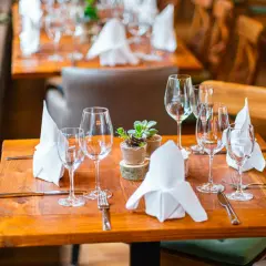 Ein gedeckter Tisch mit Sektgläsern, Servietten und einer kleinen Pflanze. Die Gläser sind bereit für den Anlass, aber wie viel passt in ein Sektglas?