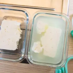 Zwei Glasbehälter zeigen, wie man Feta aufbewahren kann: ein Stück trocken, das andere in Lake.