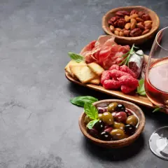 Ein Glas Roséwein als Aperitif, dazu eine Auswahl an Aufschnitt, Oliven und Nüssen. Perfekt für einen entspannten Abend.