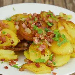 Bratkartoffeln mit gekochten Kartoffeln und Zwiebeln, garniert mit Speckwürfeln und Petersilie. Ein herzhaftes Gericht.