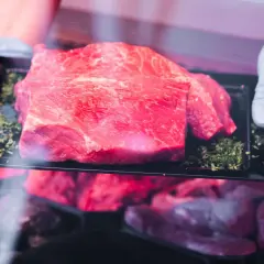 Frisch präsentiertes Rindfleisch auf einem schwarzen Teller, umgeben von Kräutern. Hoffentlich riecht das Rindfleisch nicht sauer.