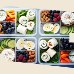 Vorbereitete Lunchboxen mit Wraps, Eiern, Beeren, Nüssen, Karotten und Gurken – perfekt als gesunde Snacks zum Mitnehmen.
