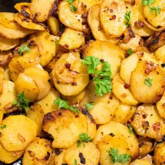 Knusprige Bratkartoffeln aus rohen Kartoffeln, goldbraun gebraten mit Zwiebeln und Speck, garniert mit Petersilie. Ein Genuss!