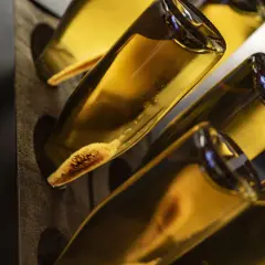Flaschen mit goldgelbem Inhalt, vielleicht ein cremiger Wein oder ein süßer Likör. Die Sedimente am Flaschenboden deuten auf eine traditionelle Herstellung hin.