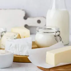 Verschiedene fermentierte Milchprodukte wie Käse, Joghurt und Butter sind auf einem Holztisch arrangiert.