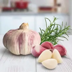 Knoblauchzehen und ein Rosmarinzweig auf einem Holztisch. Vorsicht bei der Zubereitung von Knoblauchöl, um Botulismus zu vermeiden.