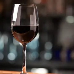 Ein Glas Rotwein, das den vollen Cabernet Sauvignon Geschmack verspricht, steht auf einem Holztisch.