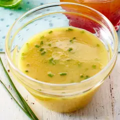 Ein Glas mit cremigem honig-senf-dressing wie im restaurant, garniert mit Schnittlauch.