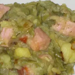 Ein herzhafter saure bohnen eintopf mit Kartoffeln und rosa Speckstücken, dampfend und bereit zum Genießen.