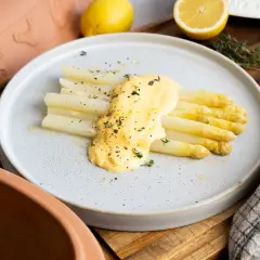 Frischer weißer Spargel aus dem Glas, verfeinert mit cremiger Sauce Hollandaise und Kräutern, garniert mit Pfeffer und Zitronenschale.