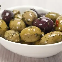 Schüssel mit grünen und violetten Oliven, mariniert mit Kräutern. Perfekt zum Oliven einlegen.
