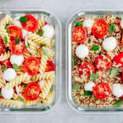 Zwei Behälter für meal prep vegetarisch: Nudelsalat mit Tomaten und Mozzarella und Quinoasalat mit Tomaten und Mozzarella.