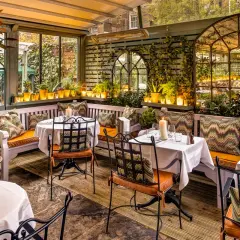 Gemütliche Terrasse mit Tischen, Kerzen und Pflanzen. Einladendes Ambiente für ein schönes Essen. Design und Genuss vereint.