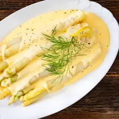 Frischer weißer Spargel mit cremiger Hollandaise, garniert mit Dill und Zitronenscheiben. Ein Klassiker der Saison.