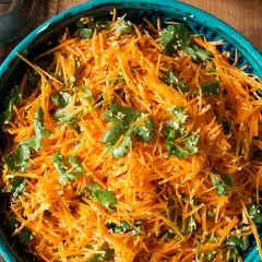 Ein erfrischender eiskraut salat aus geraspelten Karotten, garniert mit Koriander und Sesam.