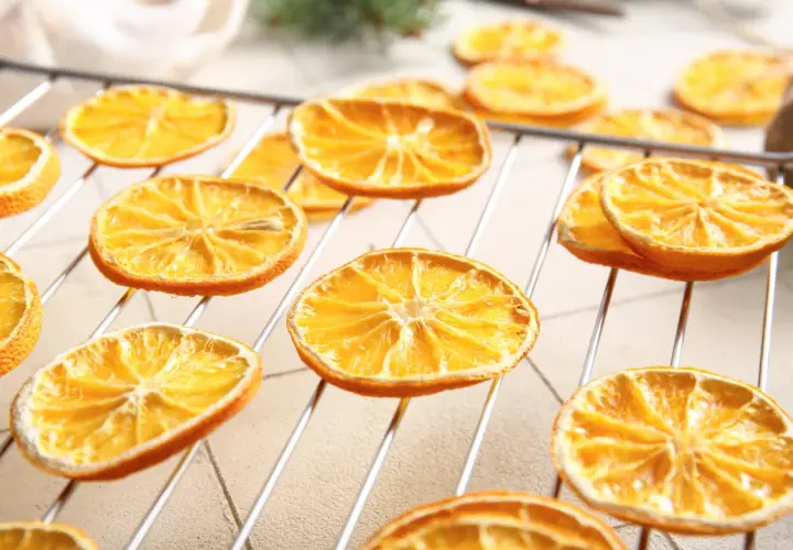 Getrocknete Orangenscheiben auf einem Rost, bereit zum Trocknen. So trocknet man Orangenscheiben für Dekorationen oder zum Verzehr.