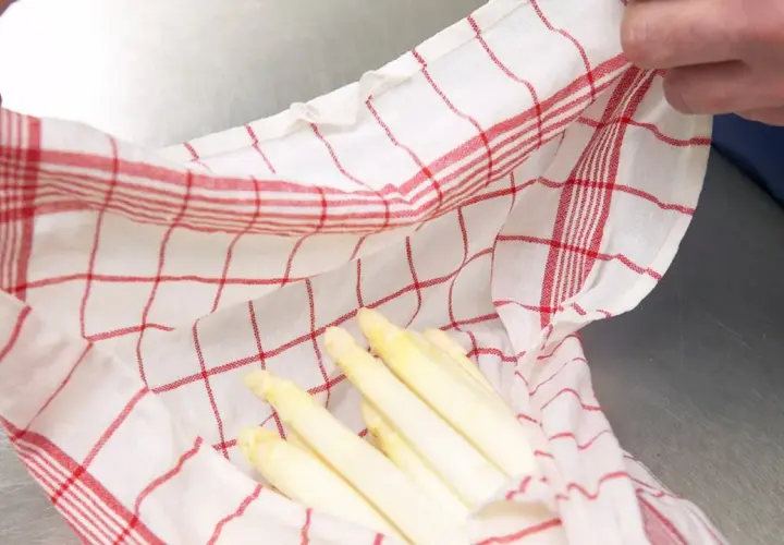 Gekochter Spargel in einem karierten Tuch. Wie lange haltbar? Frisch und appetitlich, bereit für die Lagerung.