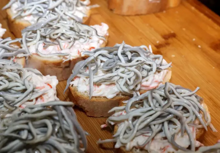 Kleine Brotscheiben mit cremiger Füllung und einem Haufen glas aal.