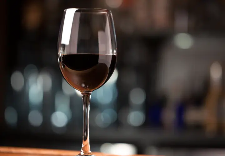 Ein Glas Rotwein, das den vollen Cabernet Sauvignon Geschmack verspricht, steht auf einem Holztisch.