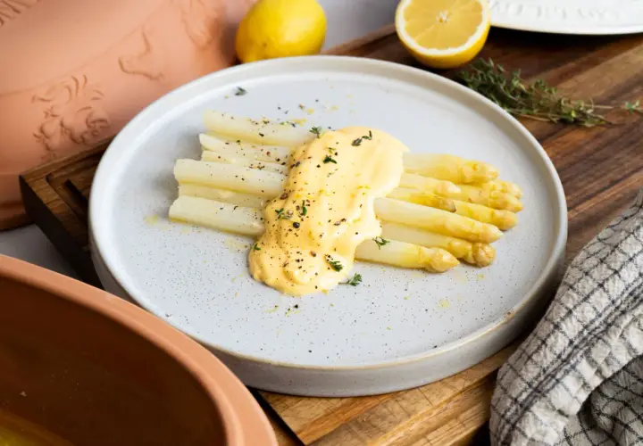 Frischer weißer Spargel aus dem Glas, verfeinert mit cremiger Sauce Hollandaise und Kräutern, garniert mit Pfeffer und Zitronenschale.