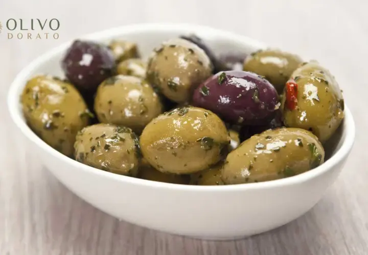 Schüssel mit grünen und violetten Oliven, mariniert mit Kräutern. Perfekt zum Oliven einlegen.