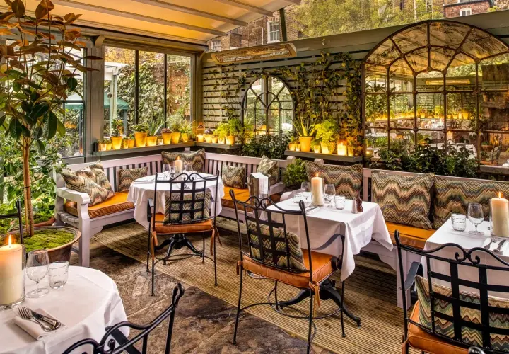 Gemütliche Terrasse mit Tischen, Kerzen und Pflanzen. Einladendes Ambiente für ein schönes Essen. Design und Genuss vereint.