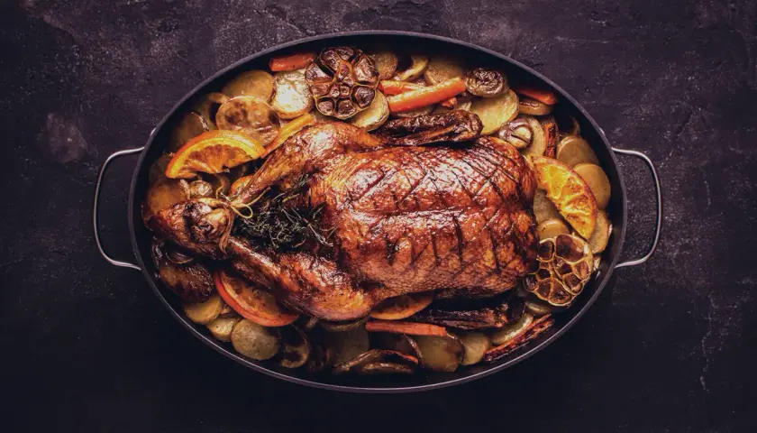 Ein goldbraun gebratener Gänsebraten mit Kartoffeln, Karotten und Orangenscheiben. Perfekt für die Frage: welcher Wein zu Gans?