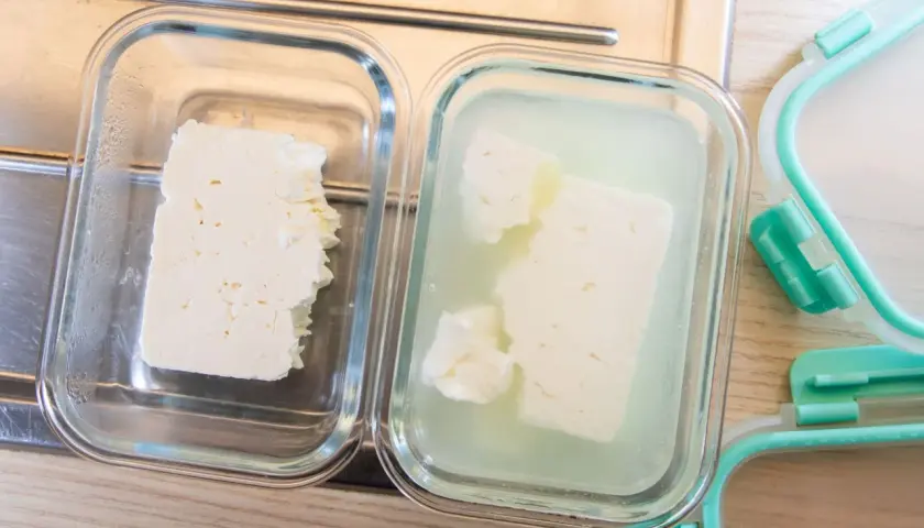 Zwei Glasbehälter zeigen, wie man Feta aufbewahren kann: ein Stück trocken, das andere in Lake.
