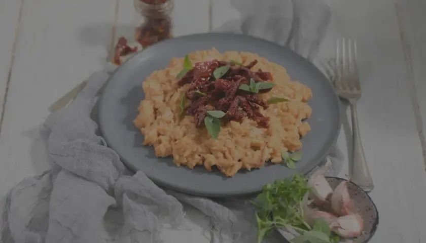 Cremiges Risotto mit getrockneten Tomaten und Basilikum. Man kann Risotto einfrieren, aber die Konsistenz verändert sich.