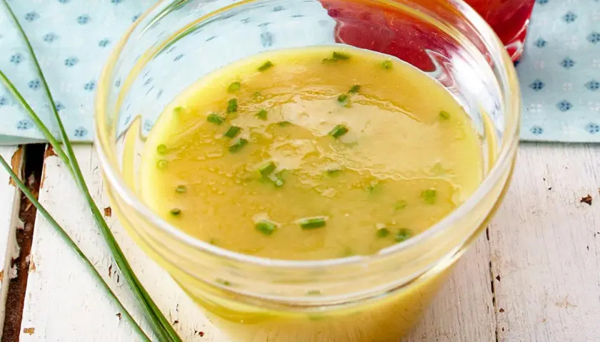 Ein Glas mit cremigem honig-senf-dressing wie im restaurant, garniert mit Schnittlauch.