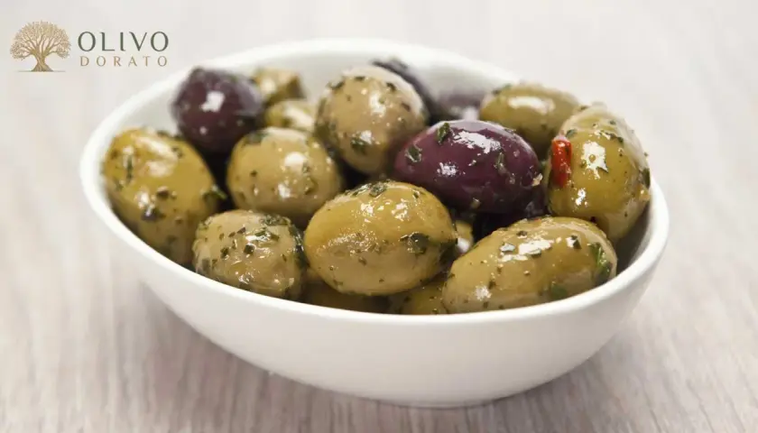 Schüssel mit grünen und violetten Oliven, mariniert mit Kräutern. Perfekt zum Oliven einlegen.
