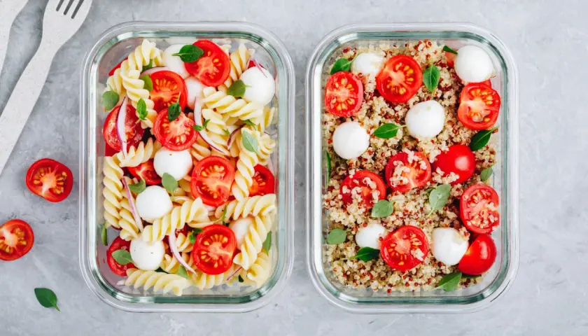 Zwei Behälter für meal prep vegetarisch: Nudelsalat mit Tomaten und Mozzarella und Quinoasalat mit Tomaten und Mozzarella.
