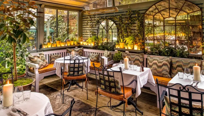 Gemütliche Terrasse mit Tischen, Kerzen und Pflanzen. Einladendes Ambiente für ein schönes Essen. Design und Genuss vereint.