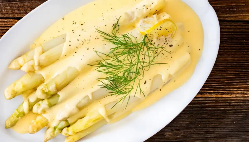 Frischer weißer Spargel mit cremiger Hollandaise, garniert mit Dill und Zitronenscheiben. Ein Klassiker der Saison.