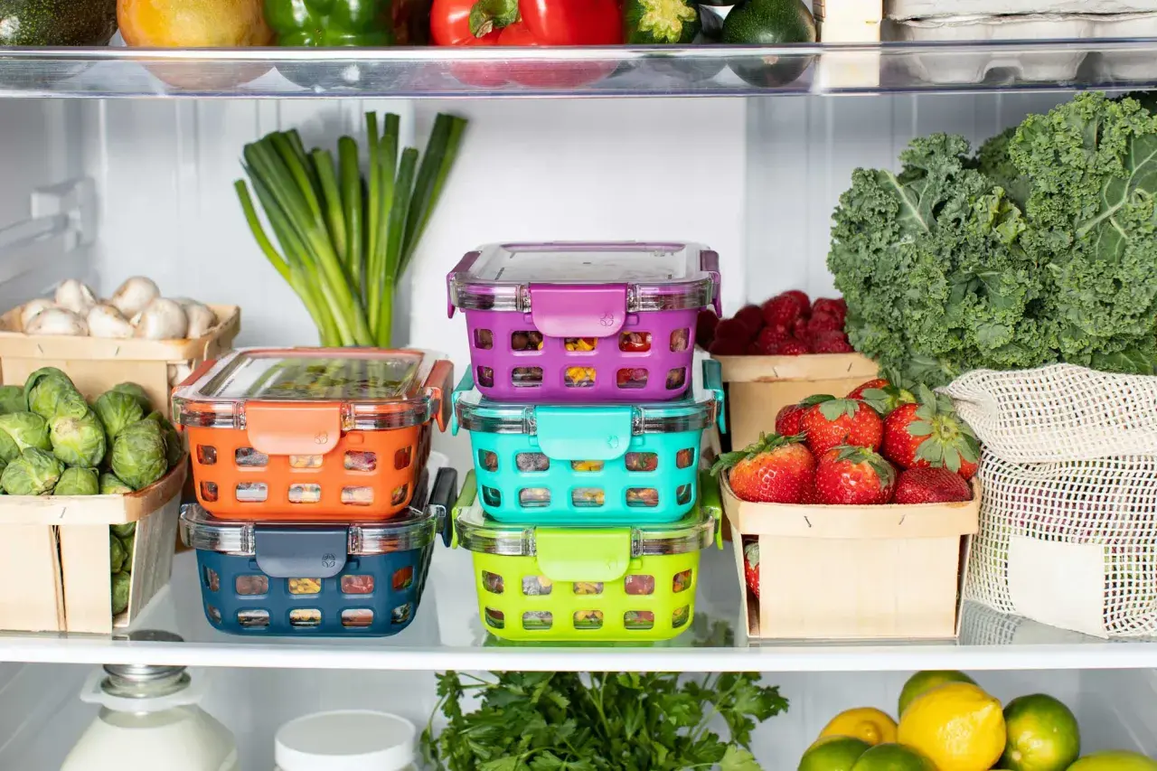 Bunte Vorratsbehälter mit Gemüse und Beeren. Oben liegen unreifes Obst und grünes Gemüse.