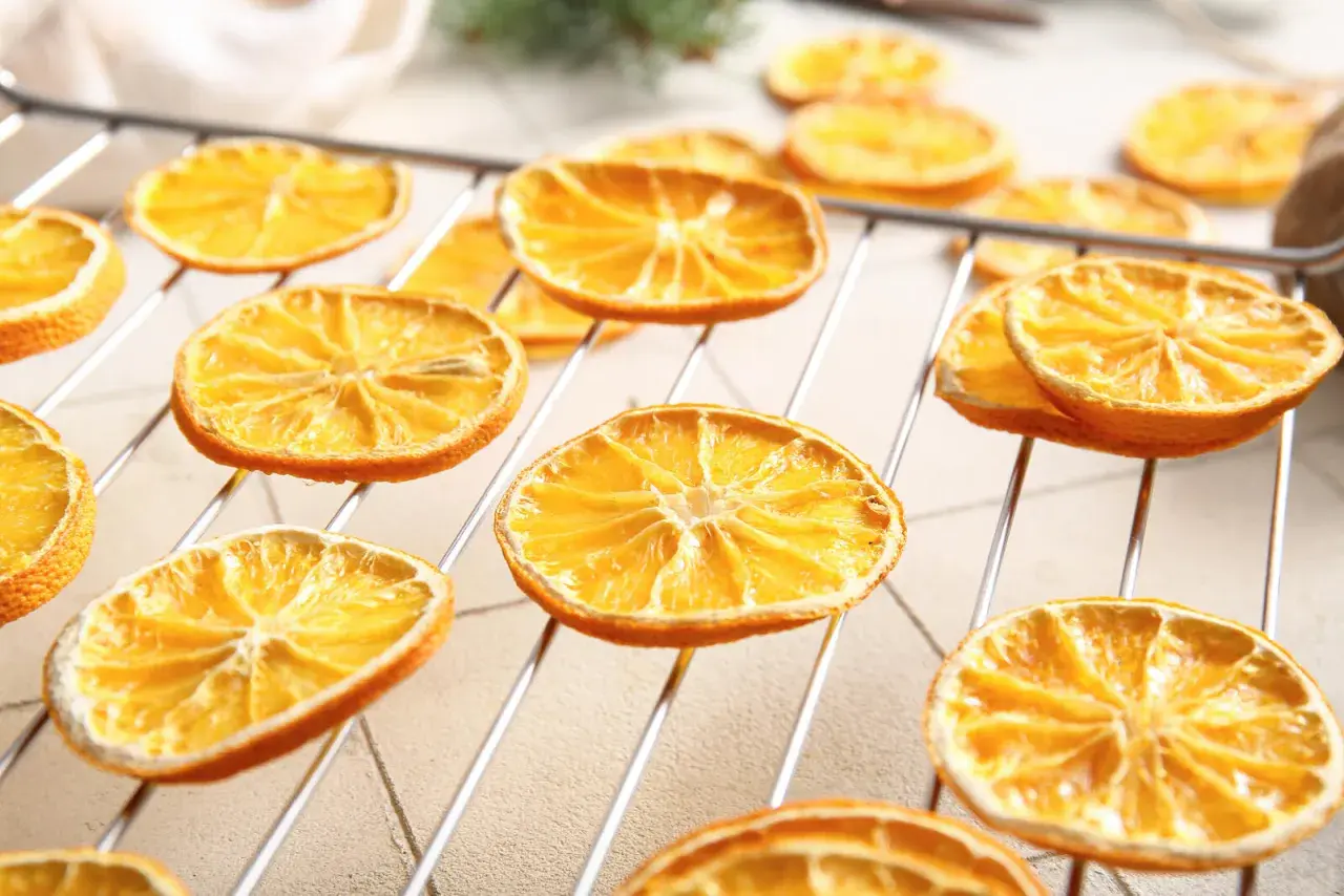 Getrocknete Orangenscheiben auf einem Rost, bereit zum Trocknen. So trocknet man Orangenscheiben für Dekorationen oder zum Verzehr.