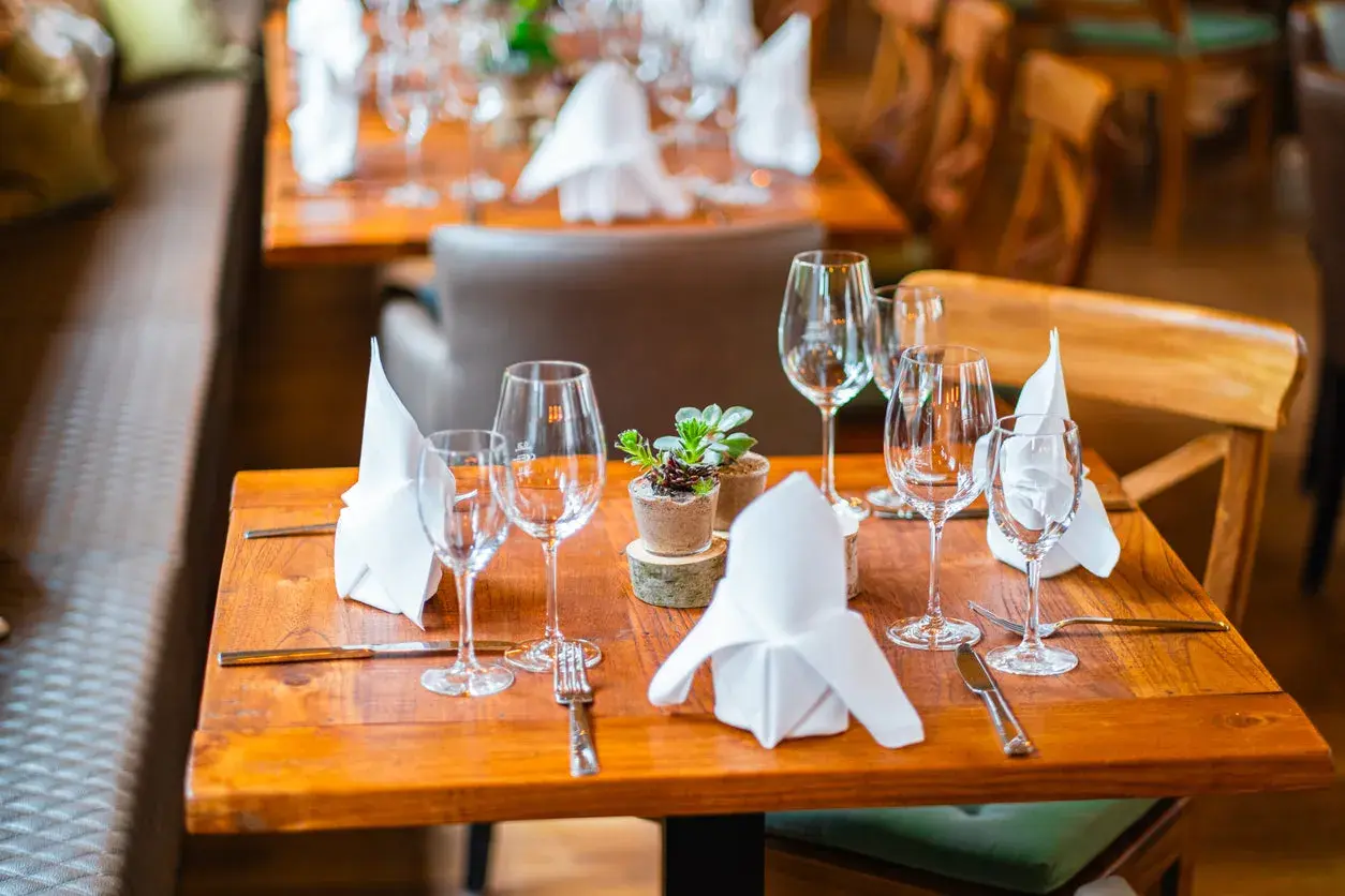 Ein gedeckter Tisch mit Sektgläsern, Servietten und einer kleinen Pflanze. Die Gläser sind bereit für den Anlass, aber wie viel passt in ein Sektglas?