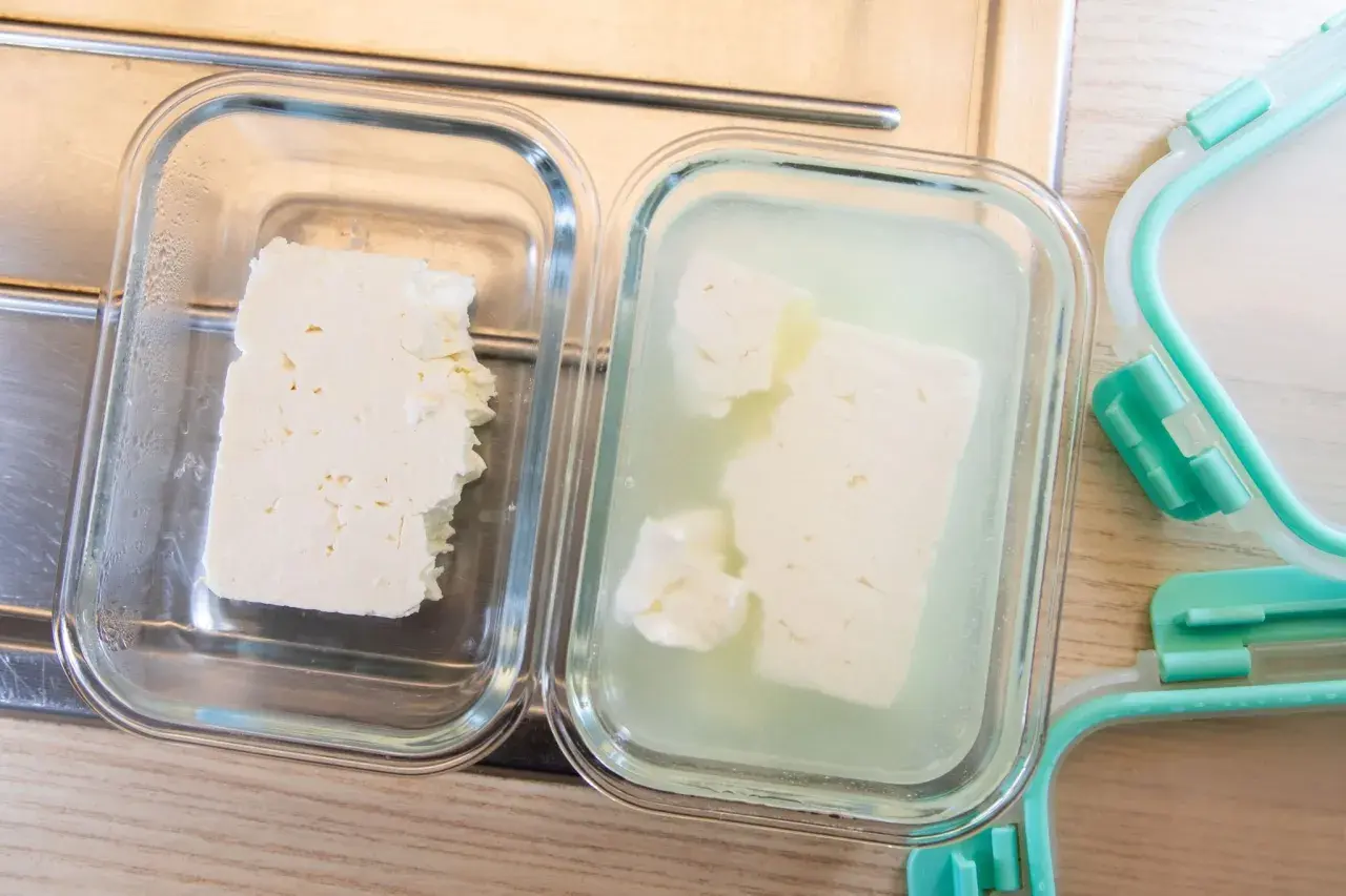 Zwei Glasbehälter zeigen, wie man Feta aufbewahren kann: ein Stück trocken, das andere in Lake.