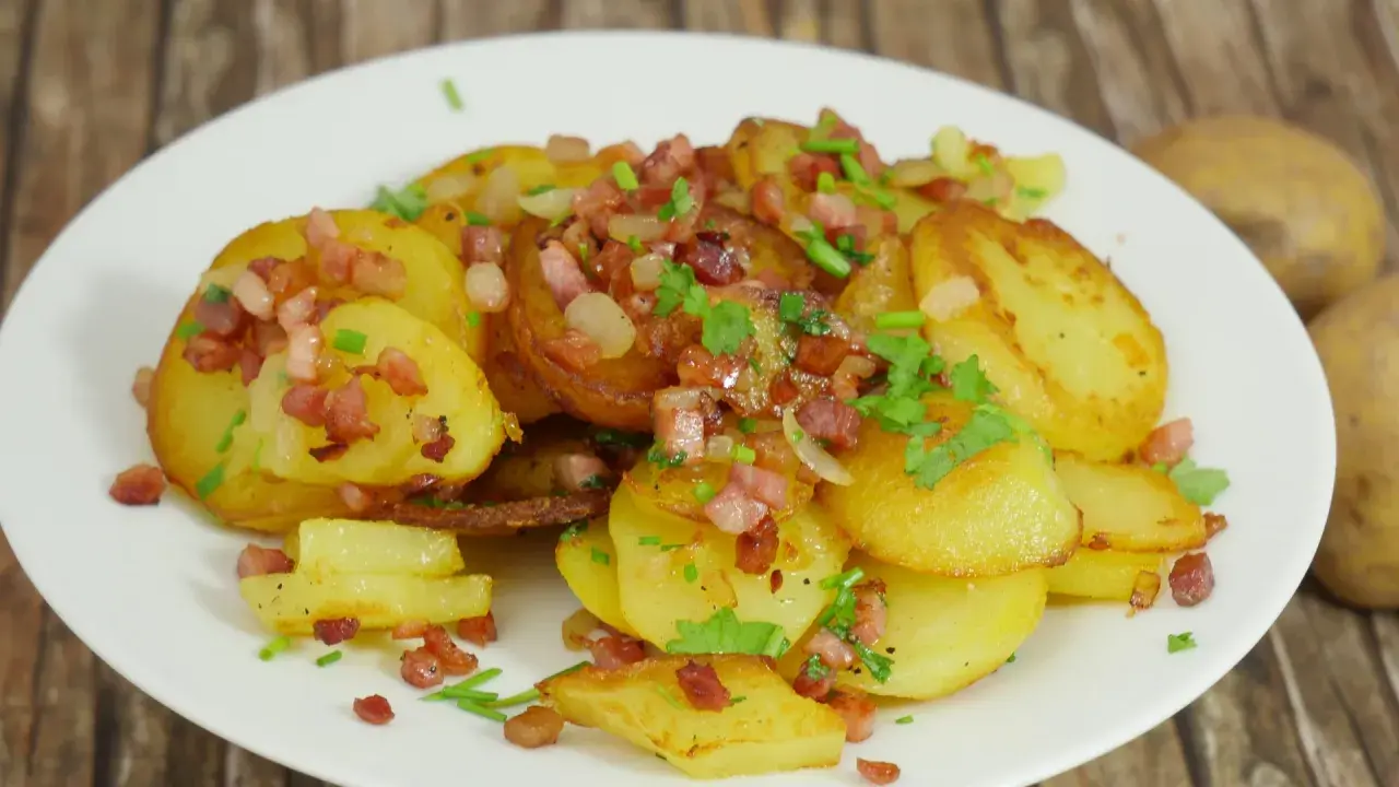 Bratkartoffeln mit gekochten Kartoffeln und Zwiebeln, garniert mit Speckwürfeln und Petersilie. Ein herzhaftes Gericht.