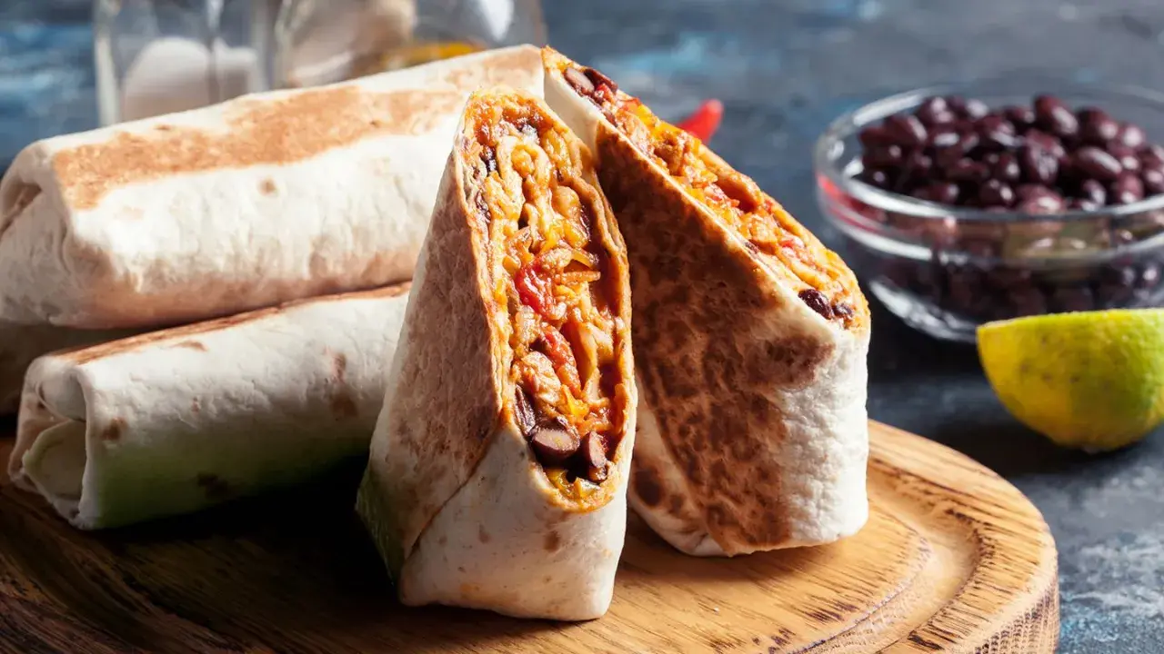 Fertige Burritos zum Einfrieren: Gestapelt und aufgeschnitten, zeigen sie eine Füllung aus Bohnen, Reis und Gemüse.