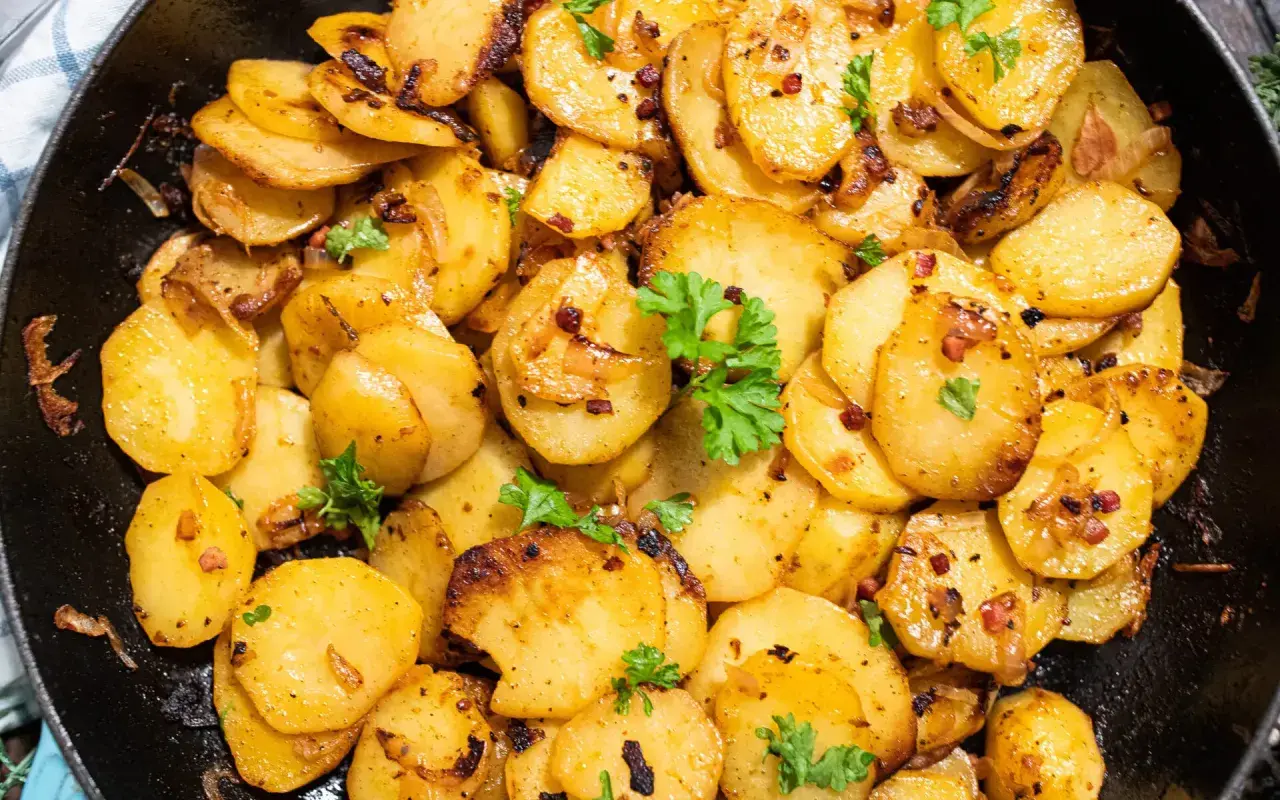 Knusprige Bratkartoffeln aus rohen Kartoffeln, goldbraun gebraten mit Zwiebeln und Speck, garniert mit Petersilie. Ein Genuss!