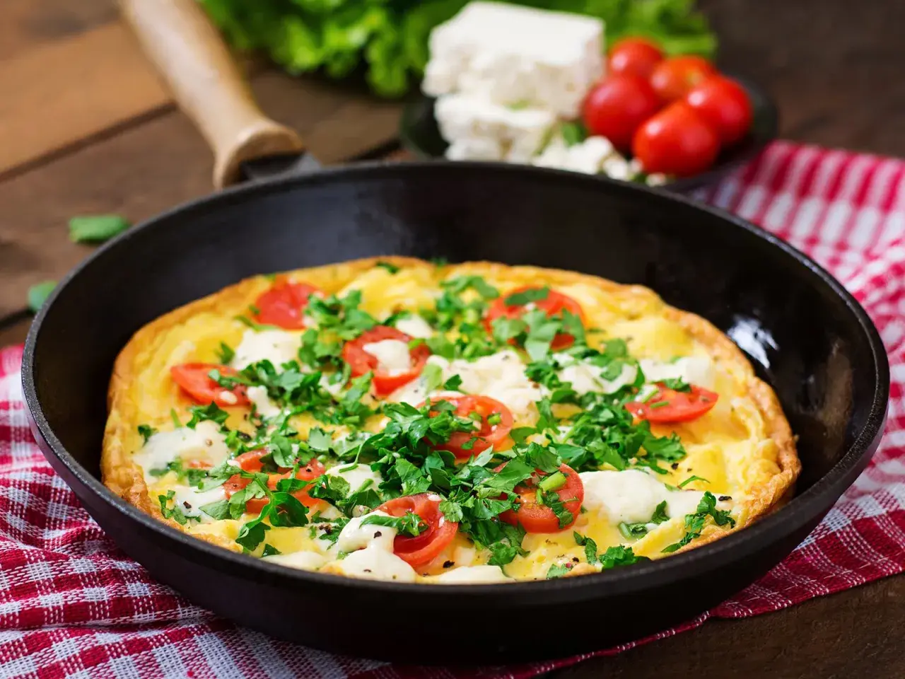 Herzhaftes Omelette mit Feta, Tomaten und Petersilie in einer Pfanne, bereit zum Servieren.