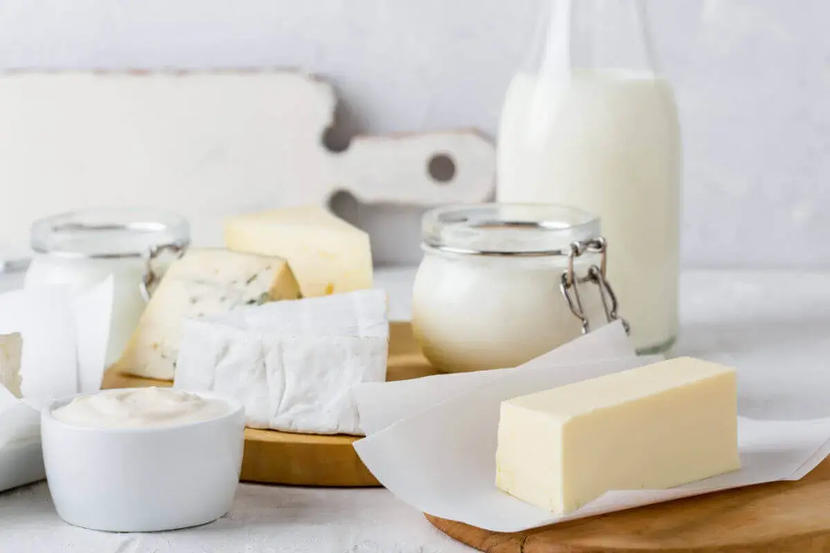 Verschiedene fermentierte Milchprodukte wie Käse, Joghurt und Butter sind auf einem Holztisch arrangiert.