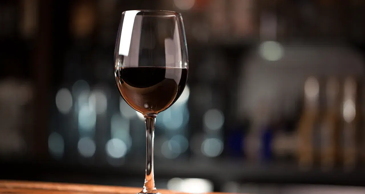 Ein Glas Rotwein, das den vollen Cabernet Sauvignon Geschmack verspricht, steht auf einem Holztisch.