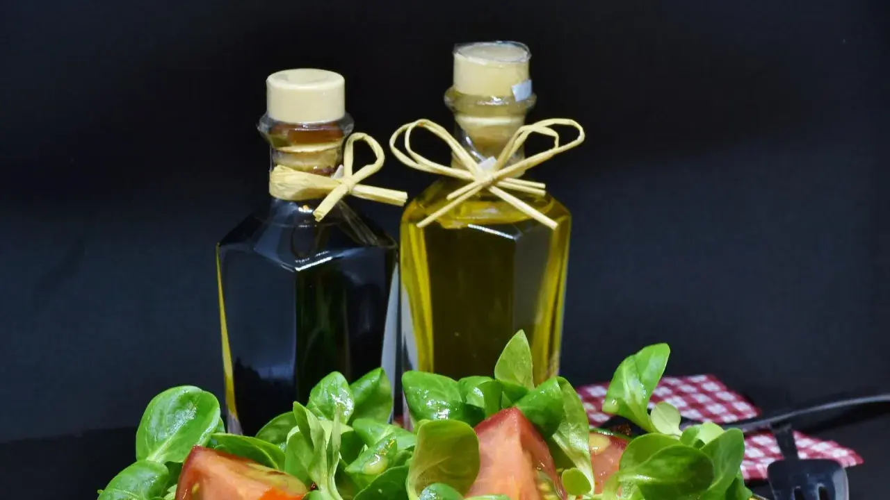 Zwei Flaschen Öl und Essig, daneben ein Salat. Wenn du zu viel Essig hast, was tun? Weniger nehmen!
