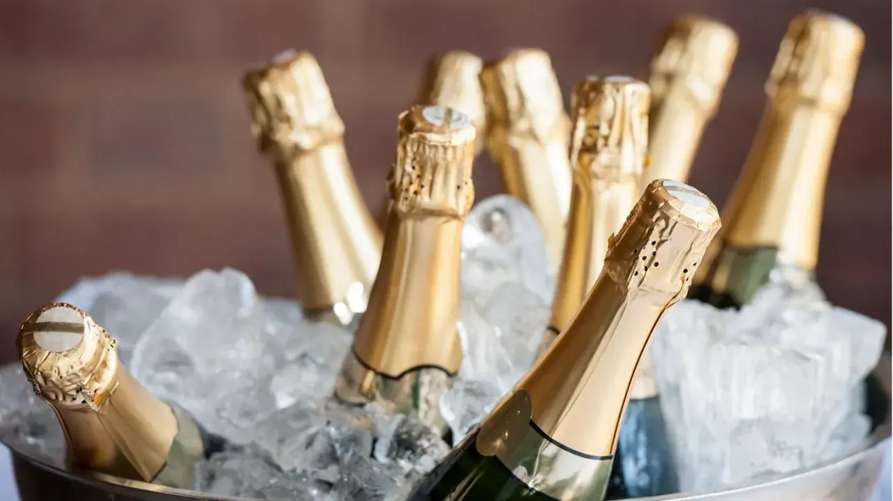 Mehrere Champagnerflaschen in goldenen Kapseln kühlen in einem Eisbad. Die perfekte Champagner Temperatur für den Genuss.